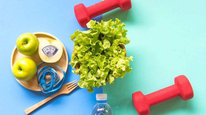 A table topped with lettuce and red plastic water bottles.