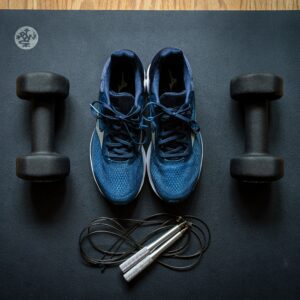 A pair of shoes and some hand weights on the floor.