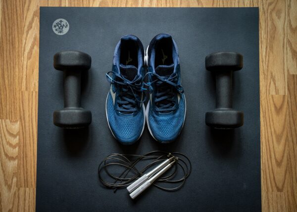 A pair of shoes and some hand weights on the floor.