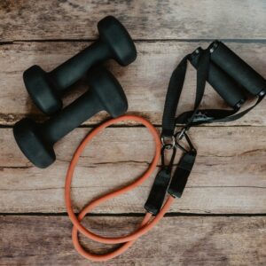 A pair of black dumbbells sitting next to an orange rope.