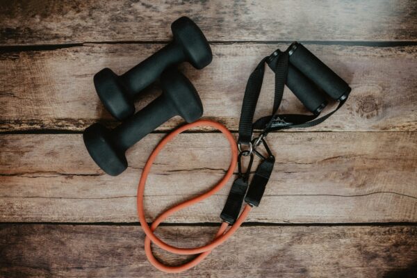 A pair of black dumbbells sitting next to an orange rope.