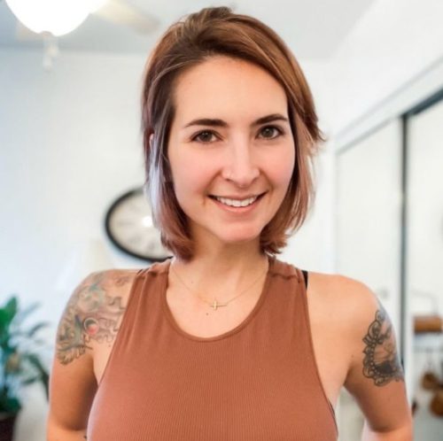 A woman with tattoos is smiling for the camera.