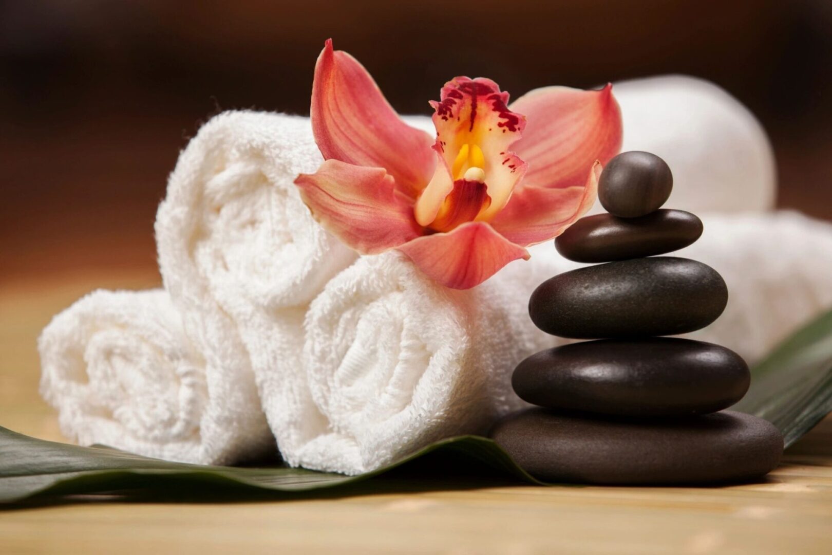 A stack of rocks and towels with an orchid on top.